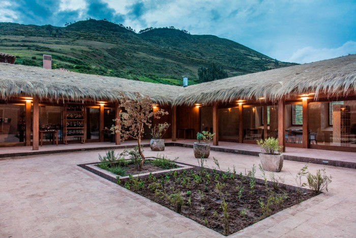 A courtyard with a thatched roof surrounded by hills 