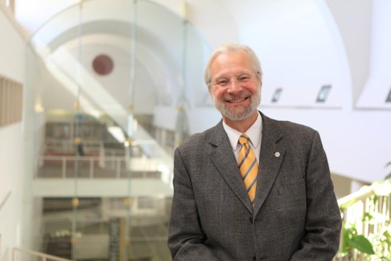 A man in a suit stands and looks at the camera. 