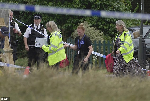 Police officers investigate after the car crashed into a school building in Wimbledon