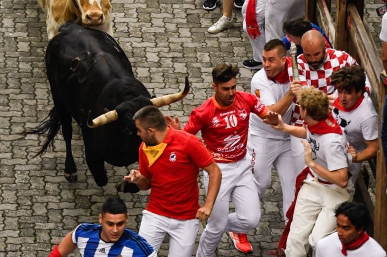 People run in front of a bull during the San Fermin festival in Pamplona, Spain.