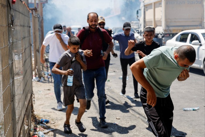 Jenin residents run away from tear gas as they confront Palestinian Authority security forces following the funeral of Palestinians killed during an Israeli operation, in Jenin 