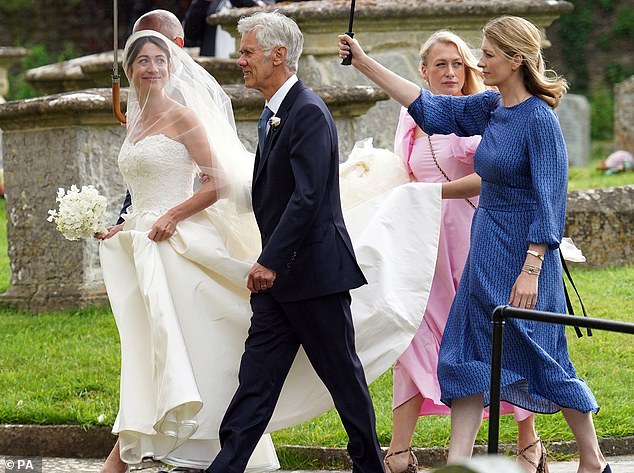 The bride and her delegation shelter from the rain under large umbrellas on Saturday aftrnoon