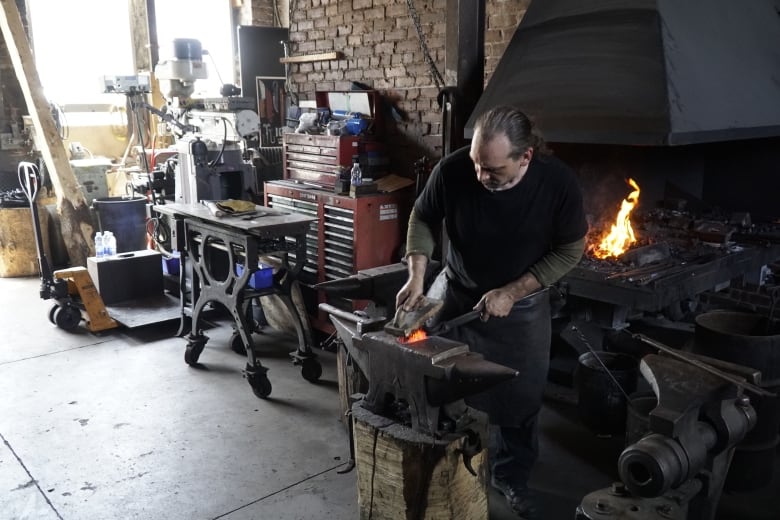 Man shaving metal on an anvil.