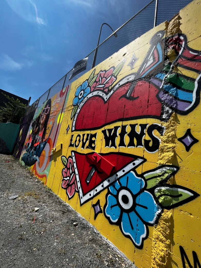 A mural showing a red heart symbol on a yellow background with "love wins" written.