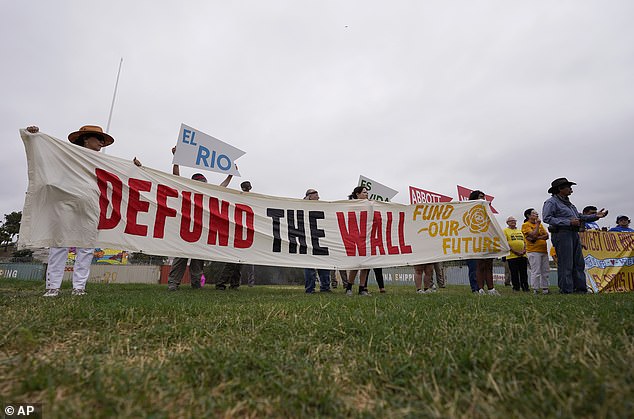 A group holds signs as they protest against buoys that are set to be deployed in the Rio Grande