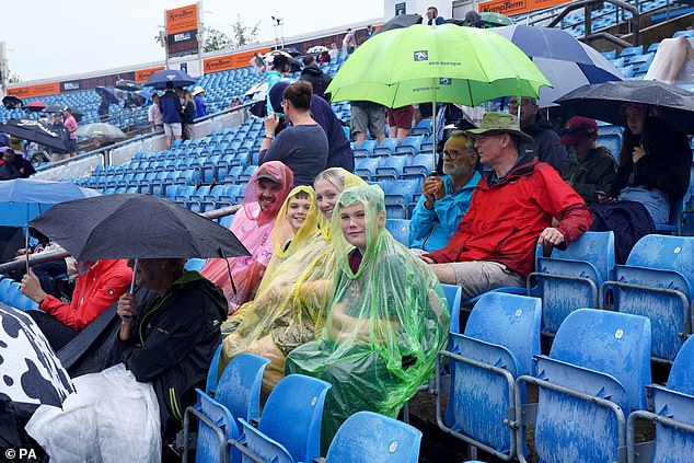 Spectators wear ponchos to shelter during rain on day three of the Ashes Series test match at Headingley, Leeds