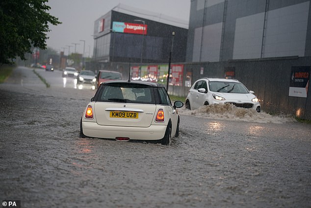 A man is caught in heavy rain in Speke, Liverpool, as the weather took a turn for the worst today