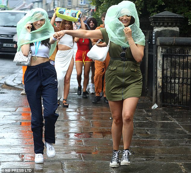 Revellers use plastic bags to protect their hair from the rain on the Ottley Run