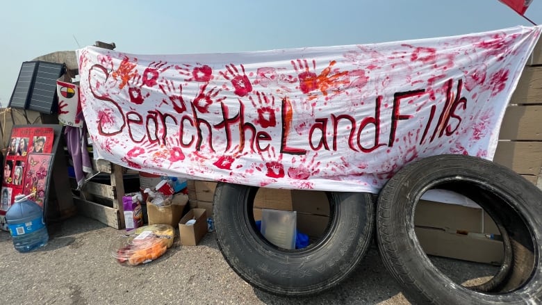 A sign that says "search the landfills" hangs in front of a blockade.