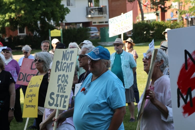 A crowd of people holding protest signs, one reading "Not right for the site."