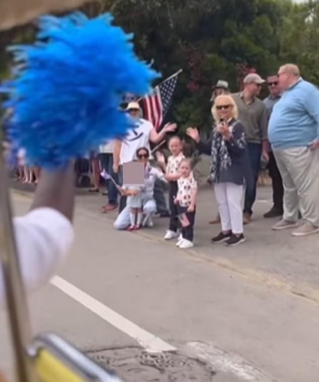 Meghan Markle, 41, can be seen cuddling up with her daughter Lilibet as they wave to performers in a 4th July parade in a new video shared on social media this week, while Prince Harry can be seen to the right of the pair