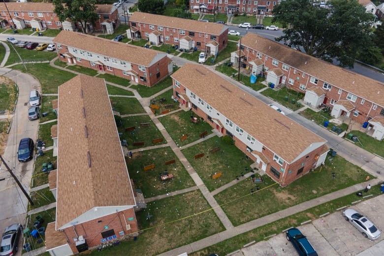 An aerial view of a neighbourhood shows tables and party supplies left outside between buildings.