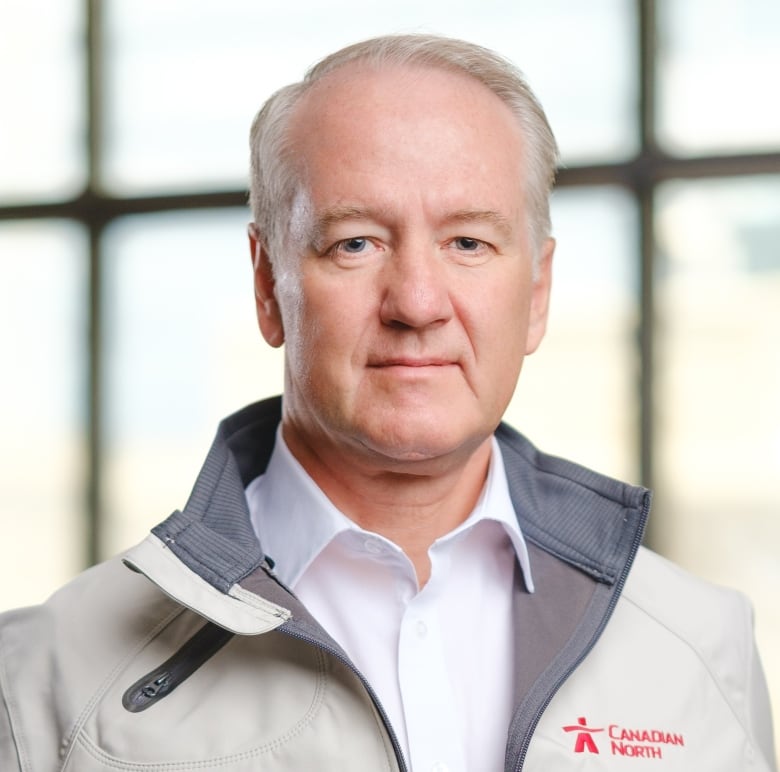 A man with white hair wearing a jacket with Canadian North on the left chest poses for the camera. 