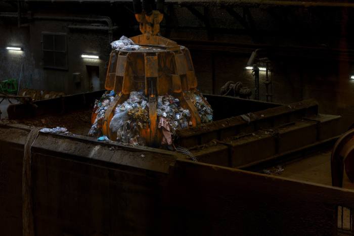 A crane loads scrap waste from pit into a combustion unit