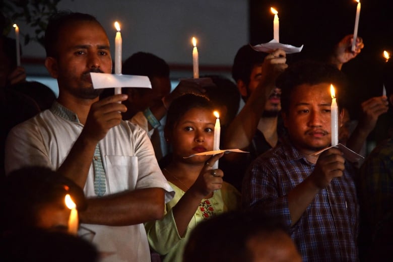 More than 10 people holding lit candles. 