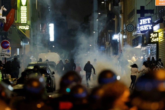 Demonstrators run as French police officers use tear gas in Paris