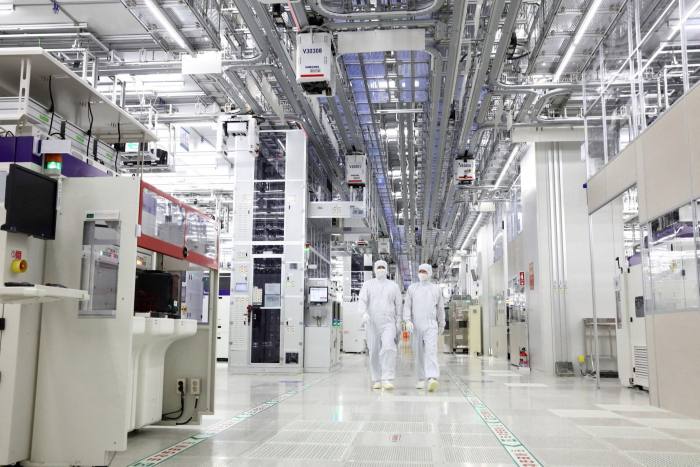 Two workers in Samsung Electronics’ chip plant in Pyeongtaek are surrounded by computer equipment