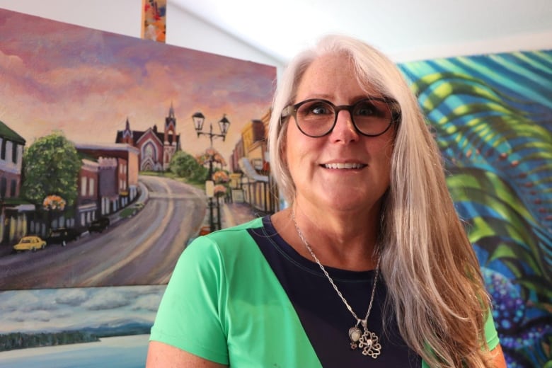 A woman stands in front of a painting.