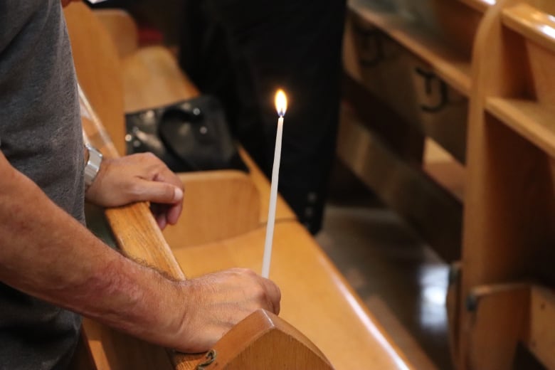 A man holds a candle stick in a church