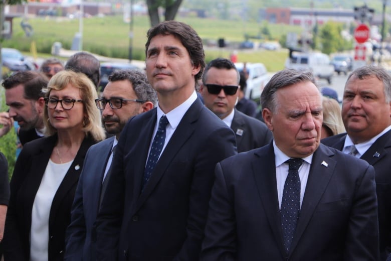 Three men stand outside. 