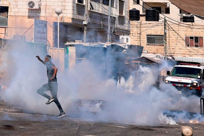 A man leaps away as the tear gas canisters land