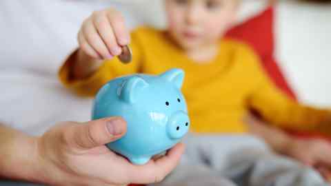 Child puts a coin into a piggy bank