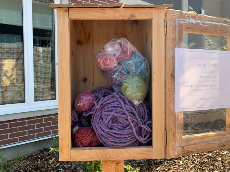 A wooden box holding several large balls of yarn.