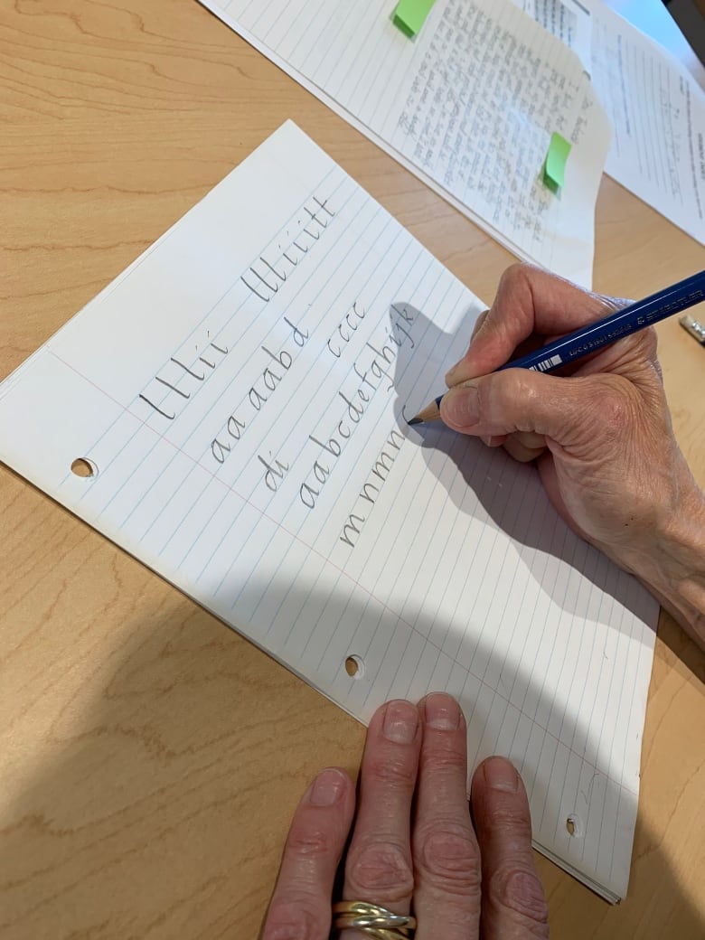 A close up photo of a hand printing letters on a sheet of lined paper.