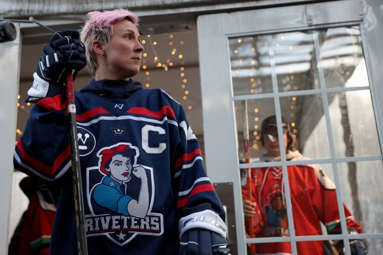 A hocker player holds her stick and looks to her left.