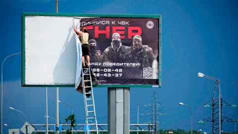 A man on a ladder removes a giant poster