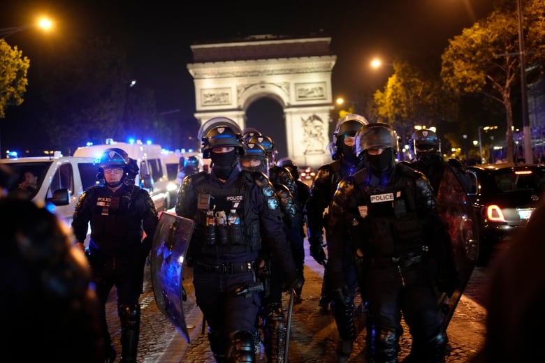 Riot police walk on a street.