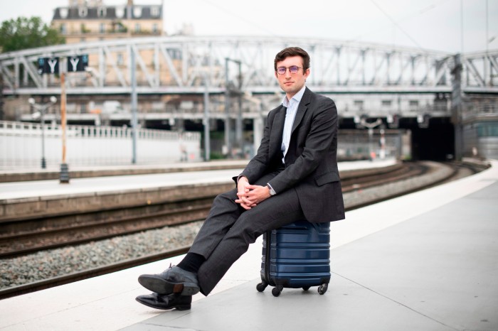 Thomas Harbor sits on his wheelie suitcase on the platform as Paris Gare du Nord