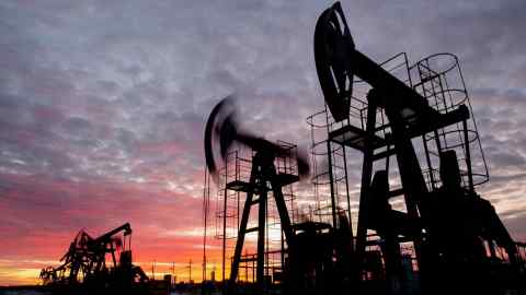 Oil pumping jacks in an oil field at sunset in Russia