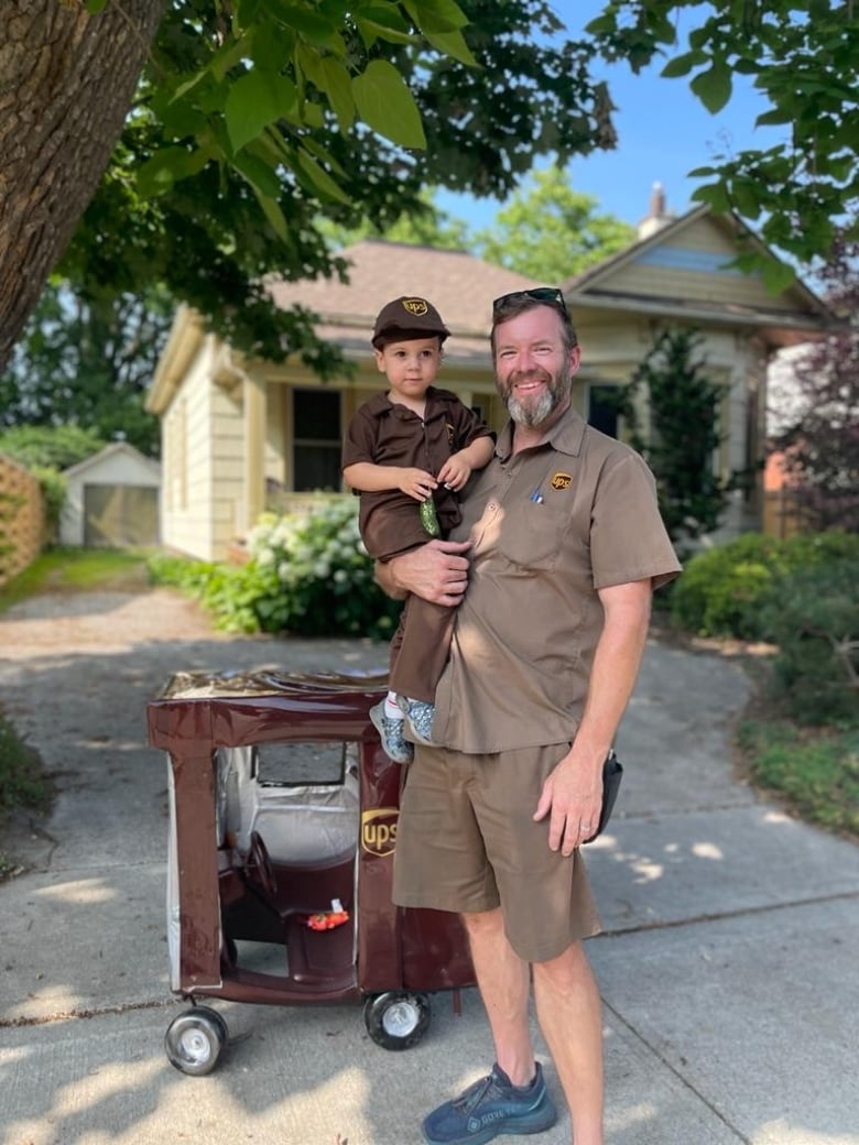 St. Thomas UPS driver, Andrew Moran, holds delivery truck enthusiast Malcolm Oshalla after visiting with the boy to mark his third birthday.