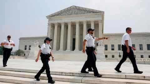 Police officers clear people from the sidewalk in front of the US Supreme Court building