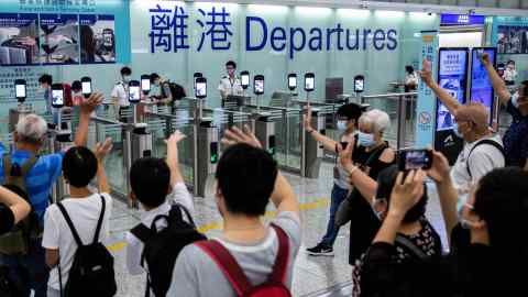 People wave goodbye as passengers make their way through the departure gates of Hong Kong International Airport in July 2021