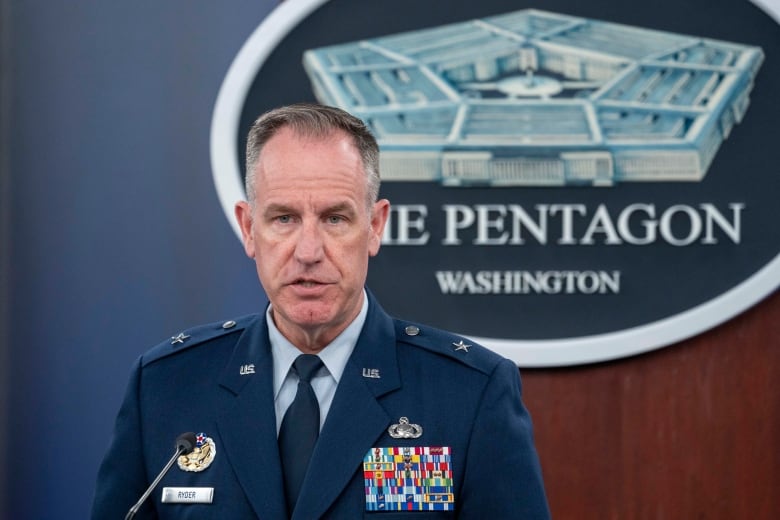 A man in a military uniform adorned with several pins is shown speaking indoors before an emblem that says, 'The Pentagon.'