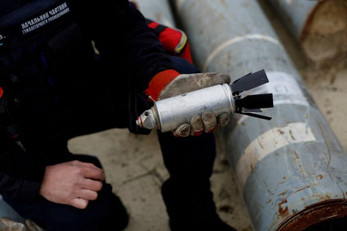 A Ukrainian military serviceman holds a defused cluster bomb