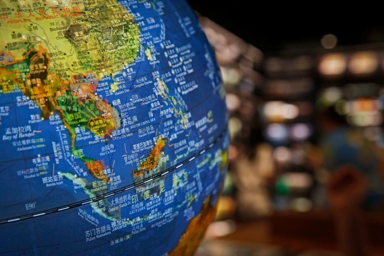 A desktop globe is shown with a blurry indoor background. 