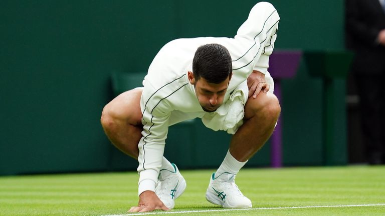 Novak Djokovic blows on the court as he inspects the moisture on it during a rain delay in their match on day one of the 2023 Wimbledon Championships at the All England Lawn Tennis and Croquet Club in Wimbledon. Picture date: Monday July 3, 2023.