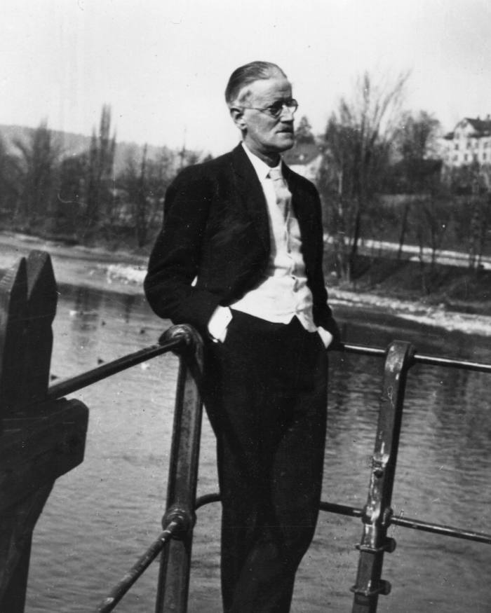 James Joyce in later life, leaning against a railing beside a river in Zürich