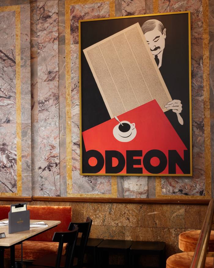 A modernist-style poster of a man reading a newspaper on the wall of the Café Odeon