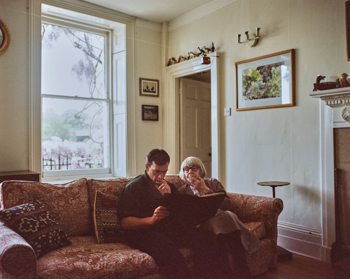 Edward and Marthe look at a scrapbook of works by Joseph