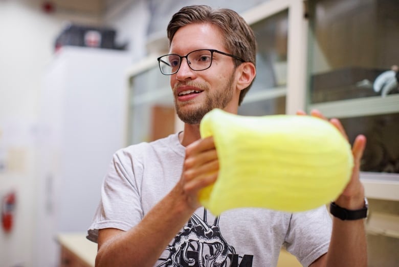 A man holds a yellow 3D printed model of a jellyfish