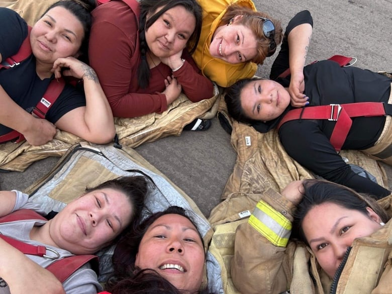 Seven women take a selfie lying down on the pavement. 