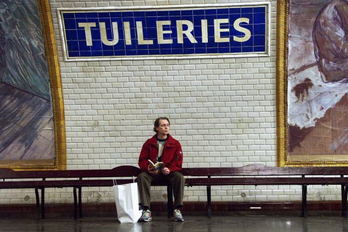 A character played by the actor Steve Buscemi sits beneath a Paris Metro sign for Tuileries