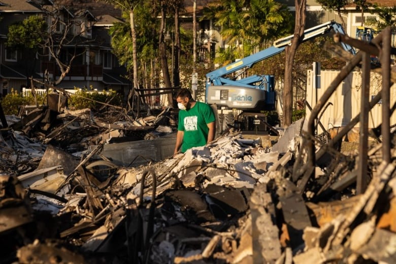 A man looks down at the remains of a charred apartment complex in the aftermath of a wildfire. 