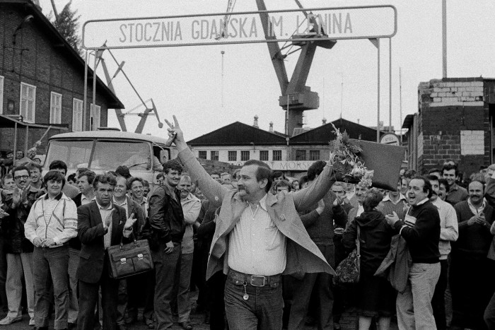 Solidarity leader Wałęsa raises his arms to a cheering crowd outside Gdańsk shipyard in June 1983