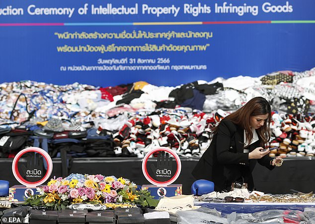 A person from a business firm inspects counterfeit goods during a destruction ceremony of goods that infringe intellectual property rights in Bangkok, Thailand, on August 31, 2023