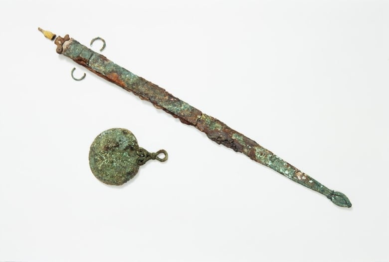 A rusty sword and mirror against a white background.